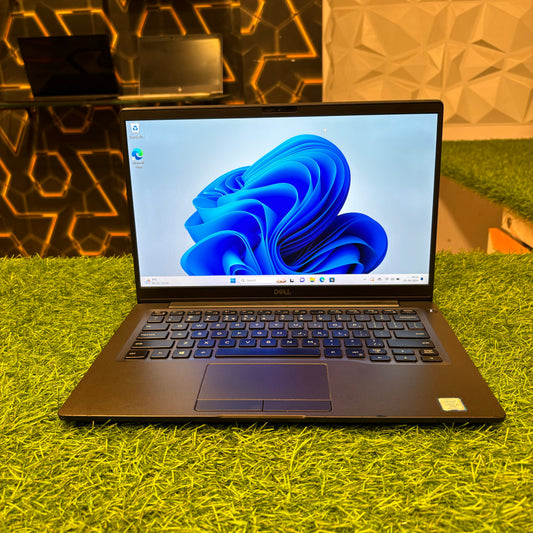 Dell Latitude 7400 laptop with a 14-inch screen displayed on a green surface, showing the screen with Windows wallpaper and the keyboard.