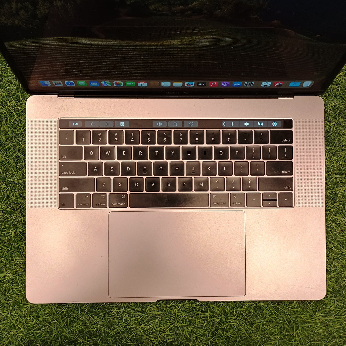 An Apple MacBook Pro with Touch Bar, displayed on a grassy surface