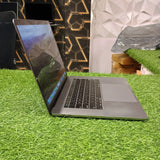 An Apple MacBook Pro with Touch Bar, displayed on a grassy surface