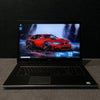 Laptop open on a dark surface with a car design on the screen