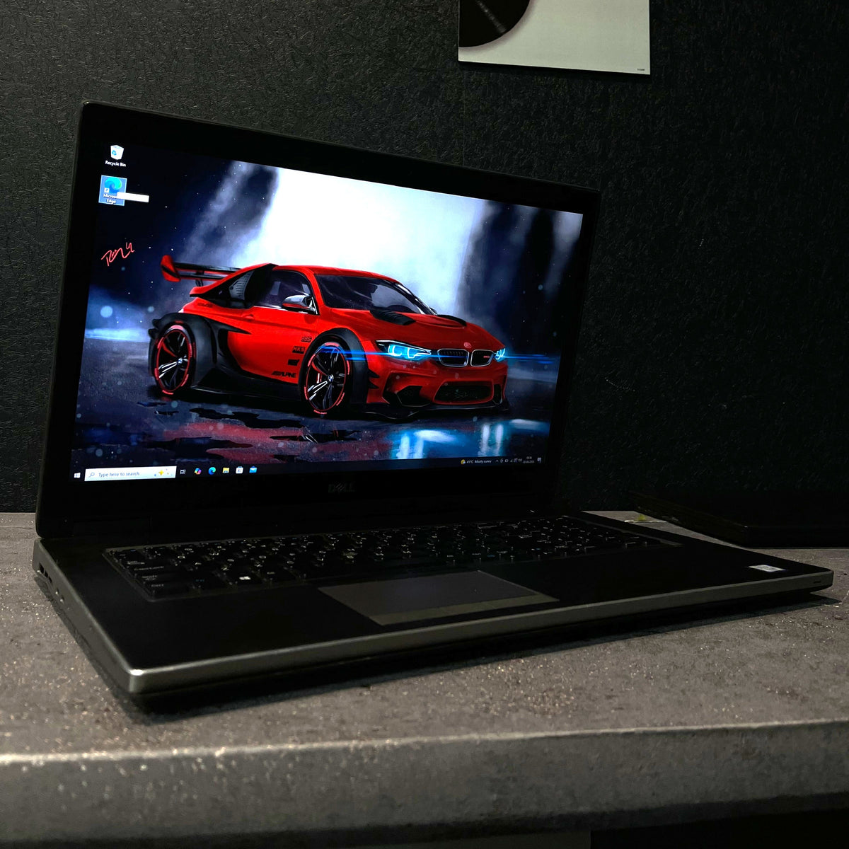 Laptop on a dark surface with a red car on the screen