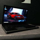 Laptop on a dark surface with a red car on the screen
