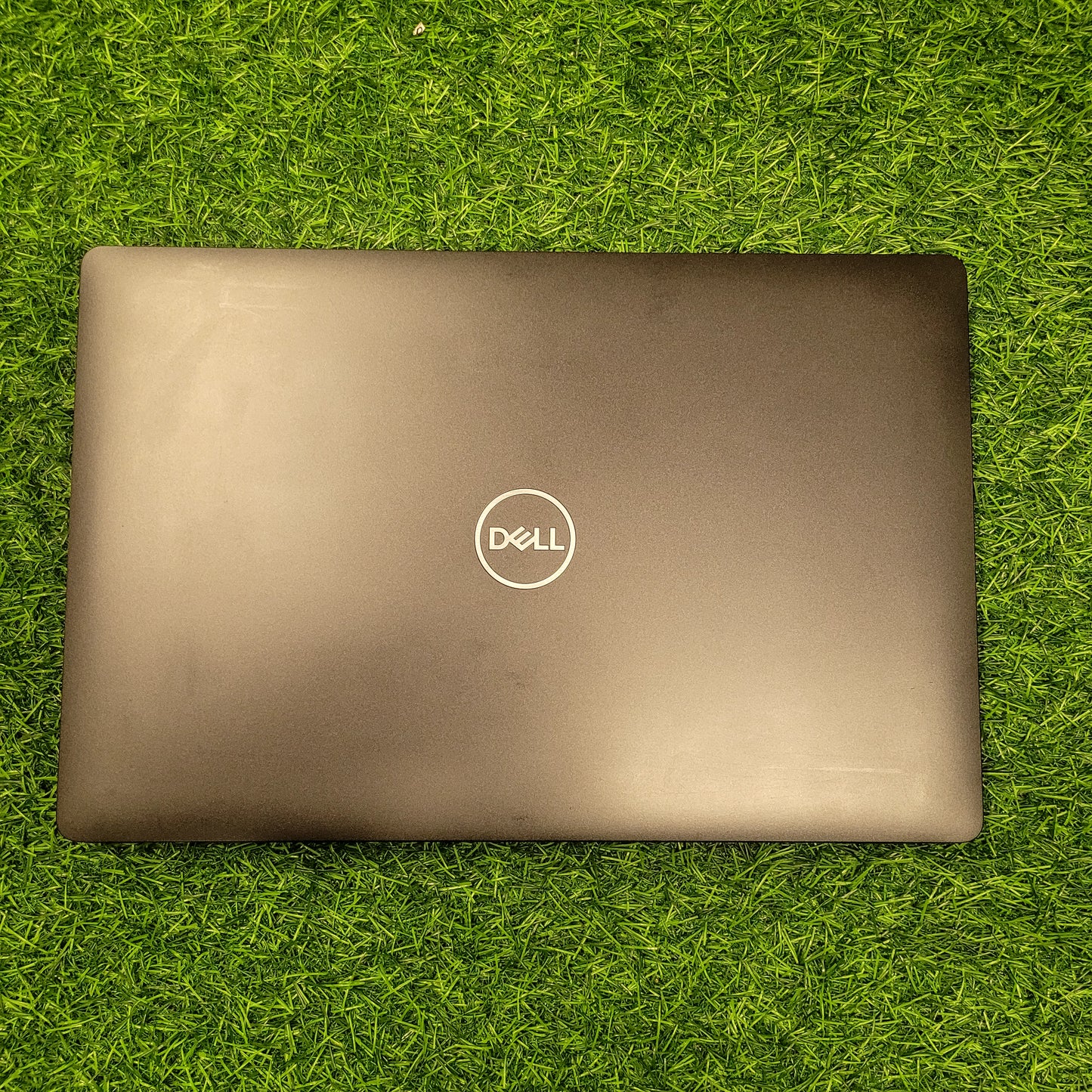 Dell Precision 3541 laptop in black color, closed, placed on green grass.