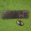 HP wireless keyboard and mouse combo on a green grass-like surface.