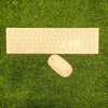 HP wireless white keyboard and mouse laid out on green grass.