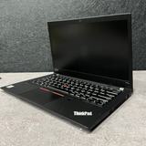 Black ThinkPad laptop on a gray surface with a gray wall background