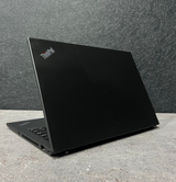 Black ThinkPad laptop on a concrete surface with a dark gray wall background