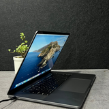 Laptop on a desk with a scenic wallpaper, plant, and vinyl record in the background.