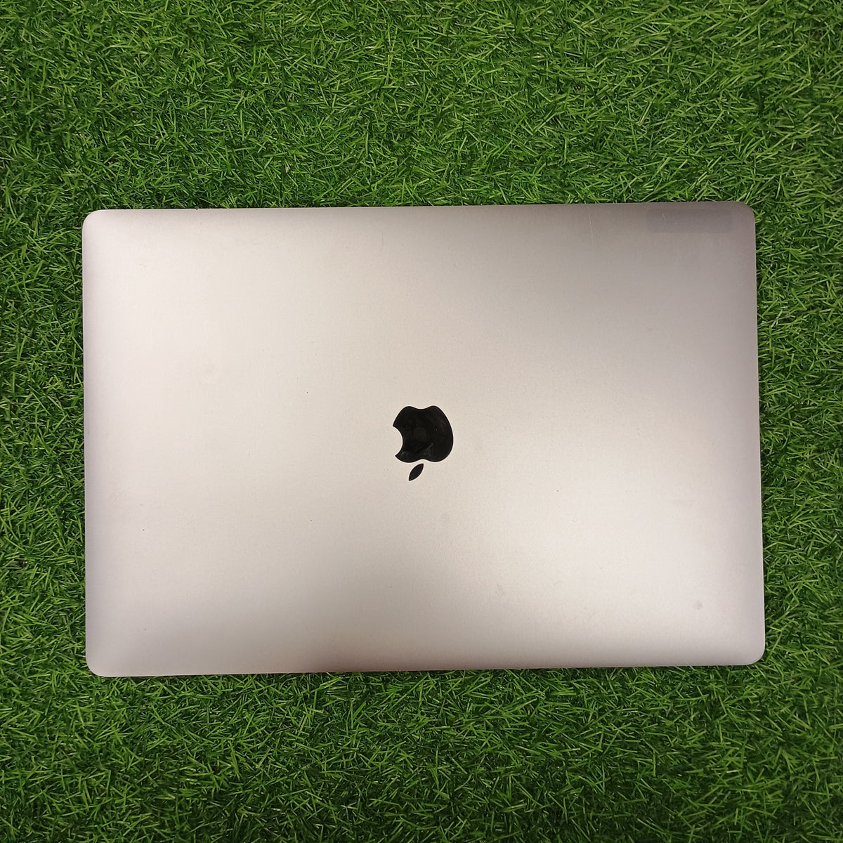 An Apple MacBook Pro  displayed on a grassy surface