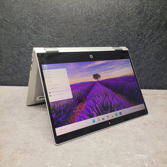 Open  HP ProBook x360 435 G8 Ryzen 7 Renewed Touchscreen Laptop displaying a scenic wallpaper on a gray surface with a dark textured wall background