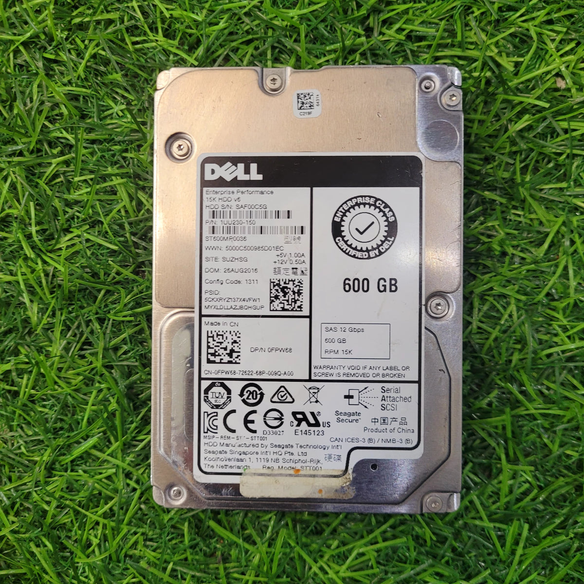 A refurbished DELL 600GB SAS 12Gb 15K 2.5 Inch Hard Disk placed on a grassy surface.