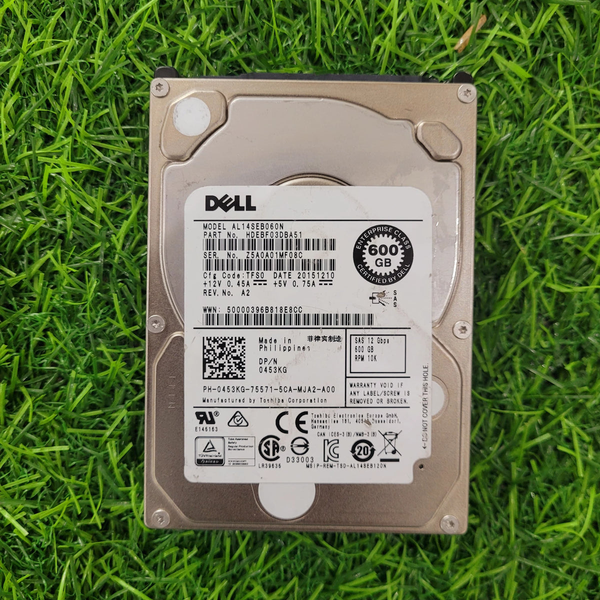 Dell 600GB 10K RPM SAS 12G 2.5-inch hard disk lying on grass.