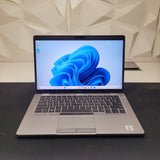 Dell Latitude 5410 laptop with a silver keyboard and a 14-inch FHD touchscreen display, open on a table showing Windows 11 operating system.
