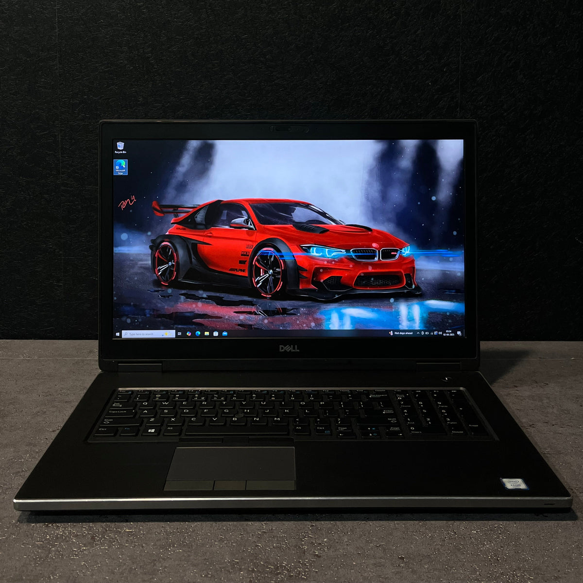 Laptop open on a dark surface with a car design on the screen
