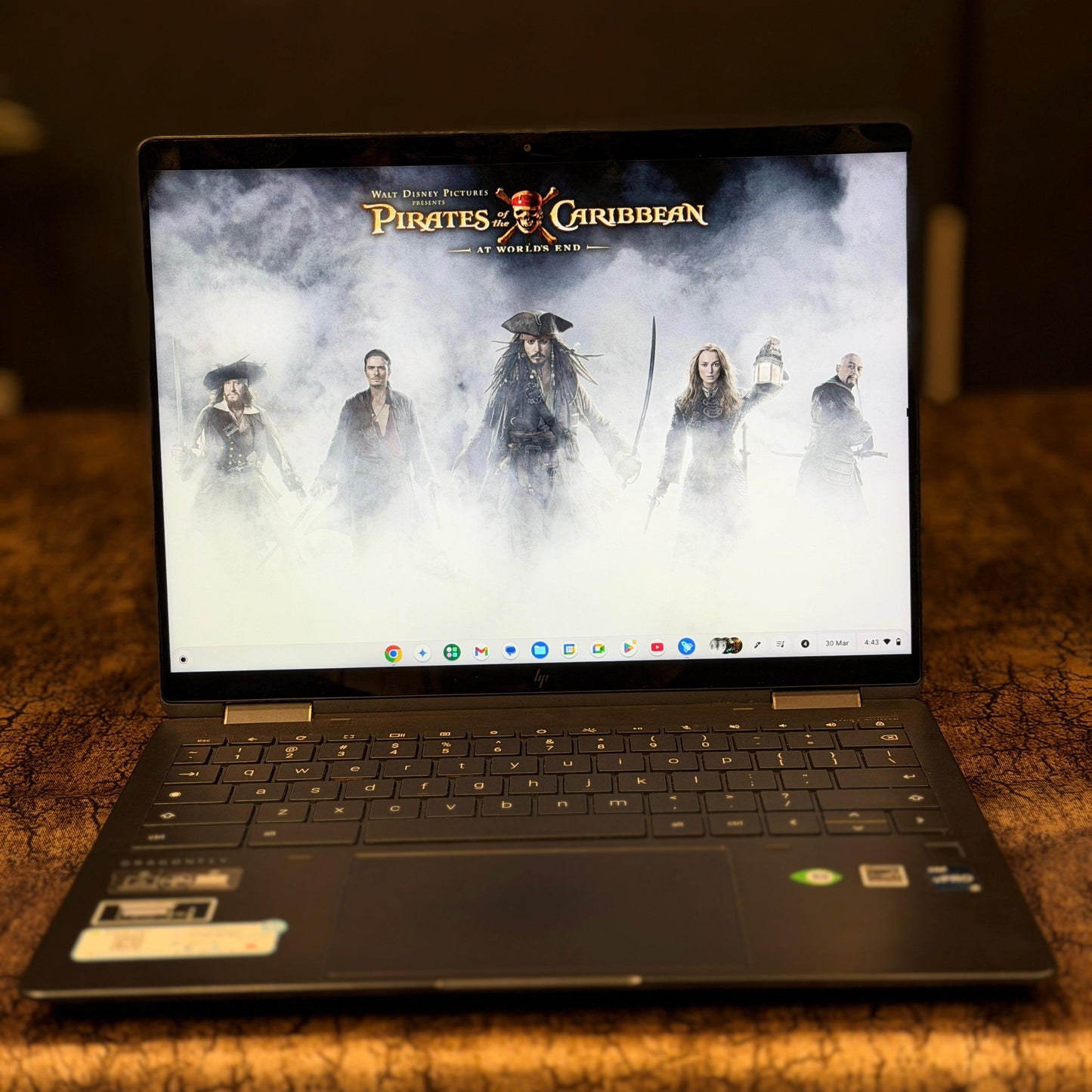 Laptop displaying 'Pirates of the Caribbean' movie poster on a wooden surface