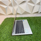 HP ProBook 440 G8 laptop with a silver color scheme, displayed on a grass-like surface against a geometric patterned backdrop.