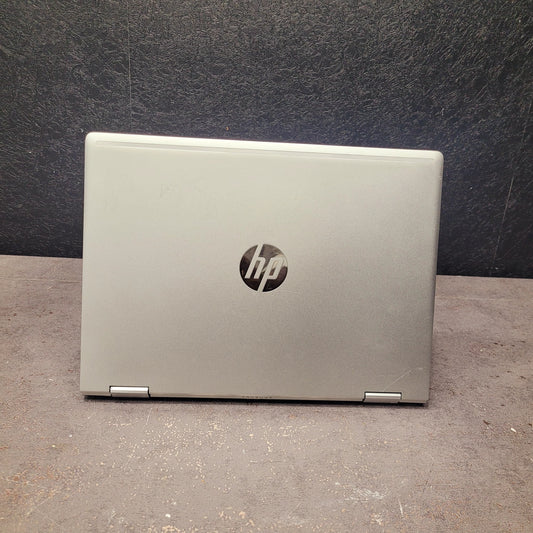 Silver HP laptop on a dark surface with a dark background