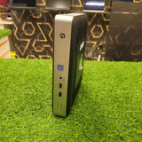 HP T628 Thin Client Computer standing upright on a grass-like surface, showcasing its side profile which includes ports and branding.