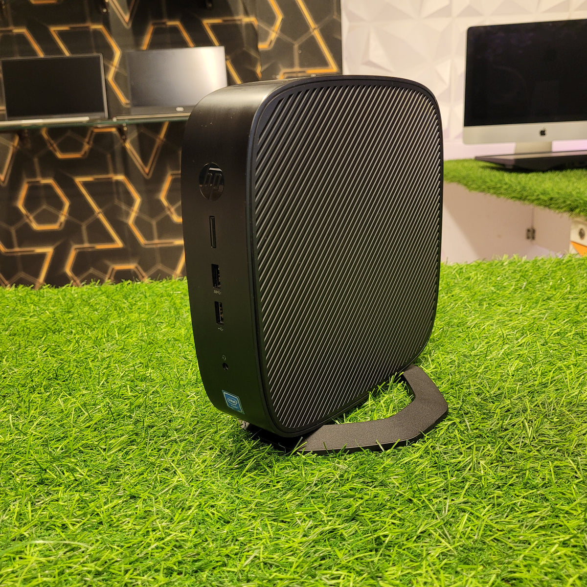 HP t638 Thin Client Computer placed on a grass-like surface, showing its black casing with a textured design.