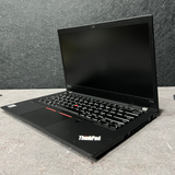 Black ThinkPad laptop on a gray surface with a gray wall background