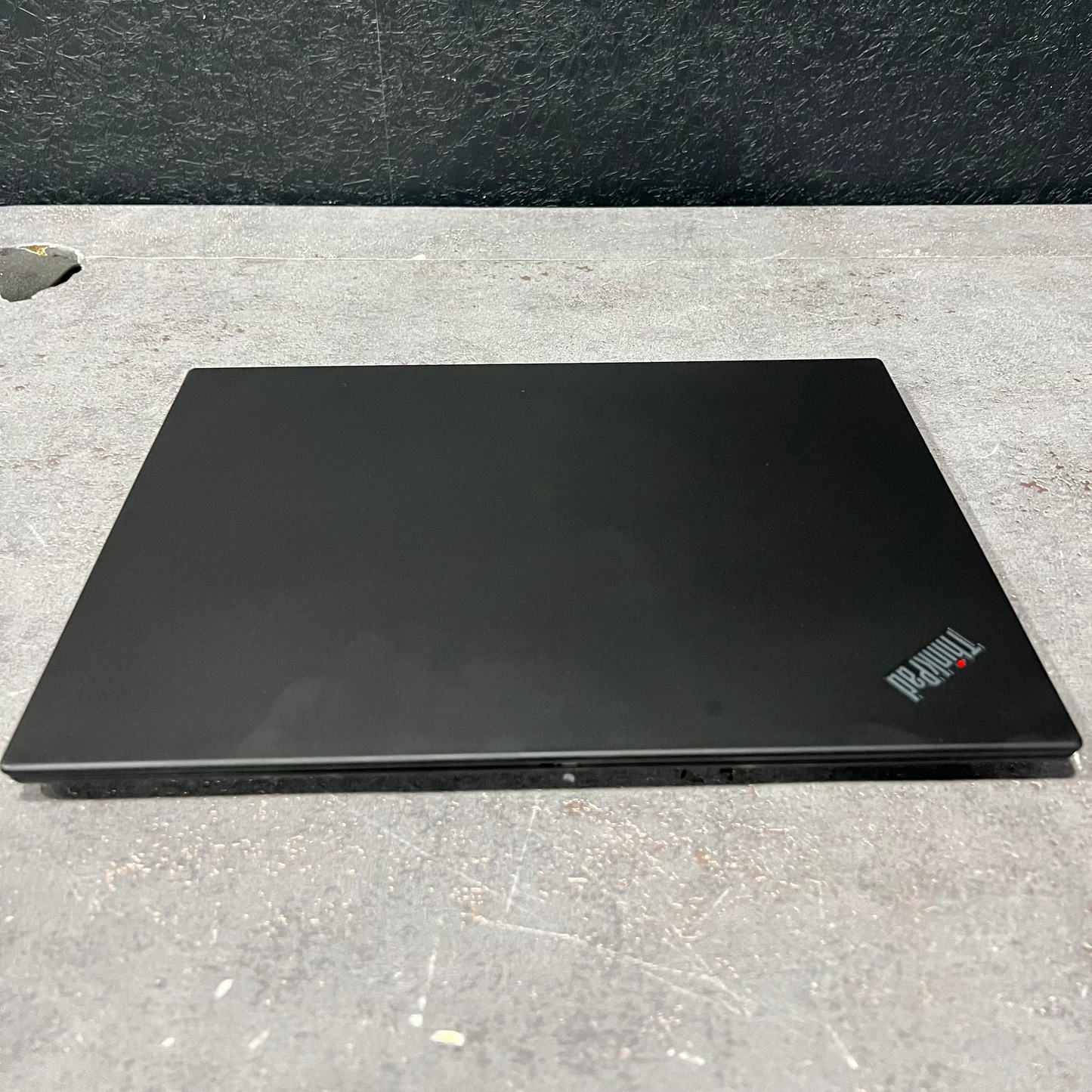 Black laptop on a gray surface with a dark background