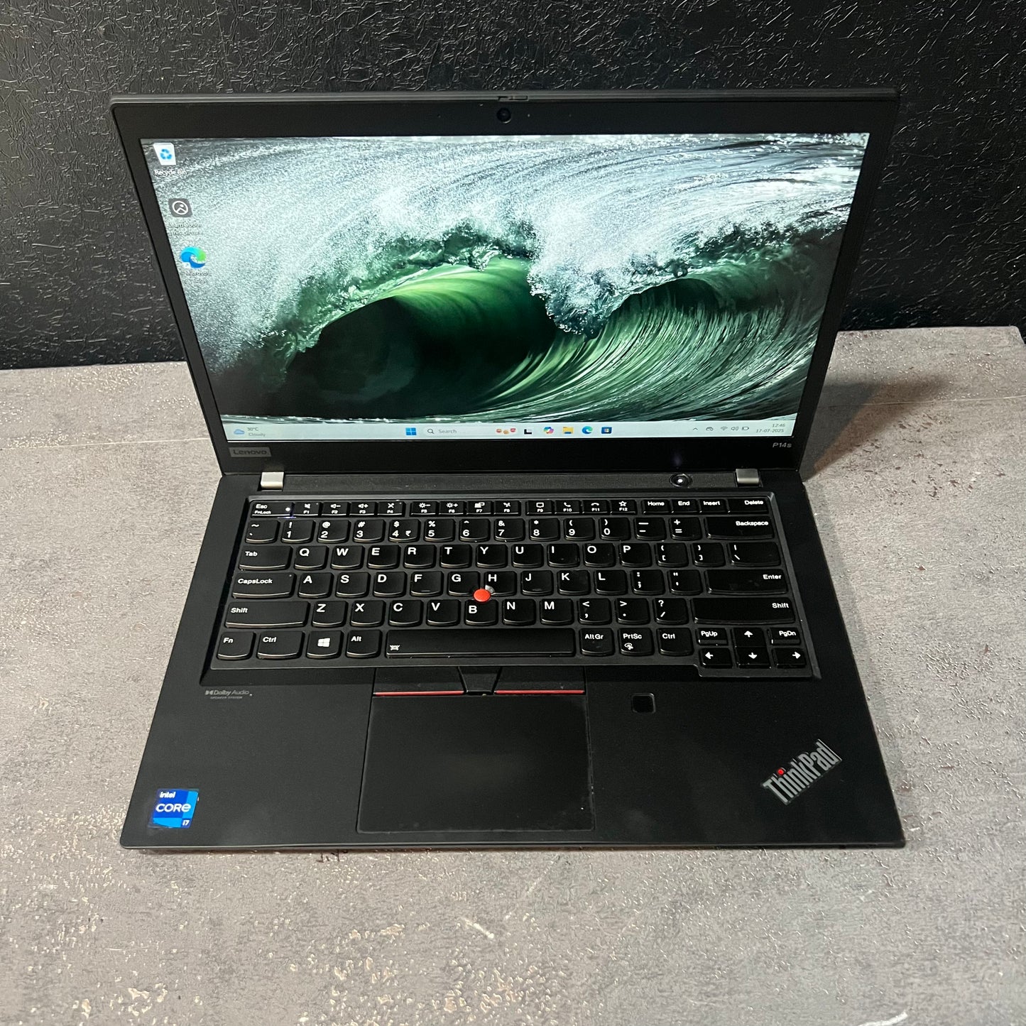 Black ThinkPad laptop open on a textured surface with a dark background