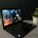 Laptop on a desk with a game displayed on the screen, surrounded by office supplies.