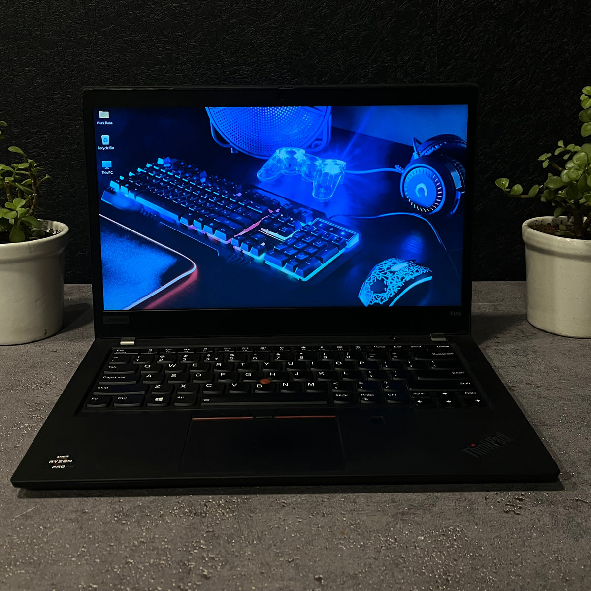 Laptop with a glowing keyboard and headphones on a dark surface