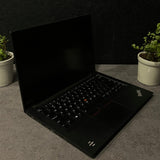 Black laptop on a dark surface with a plant in the corner