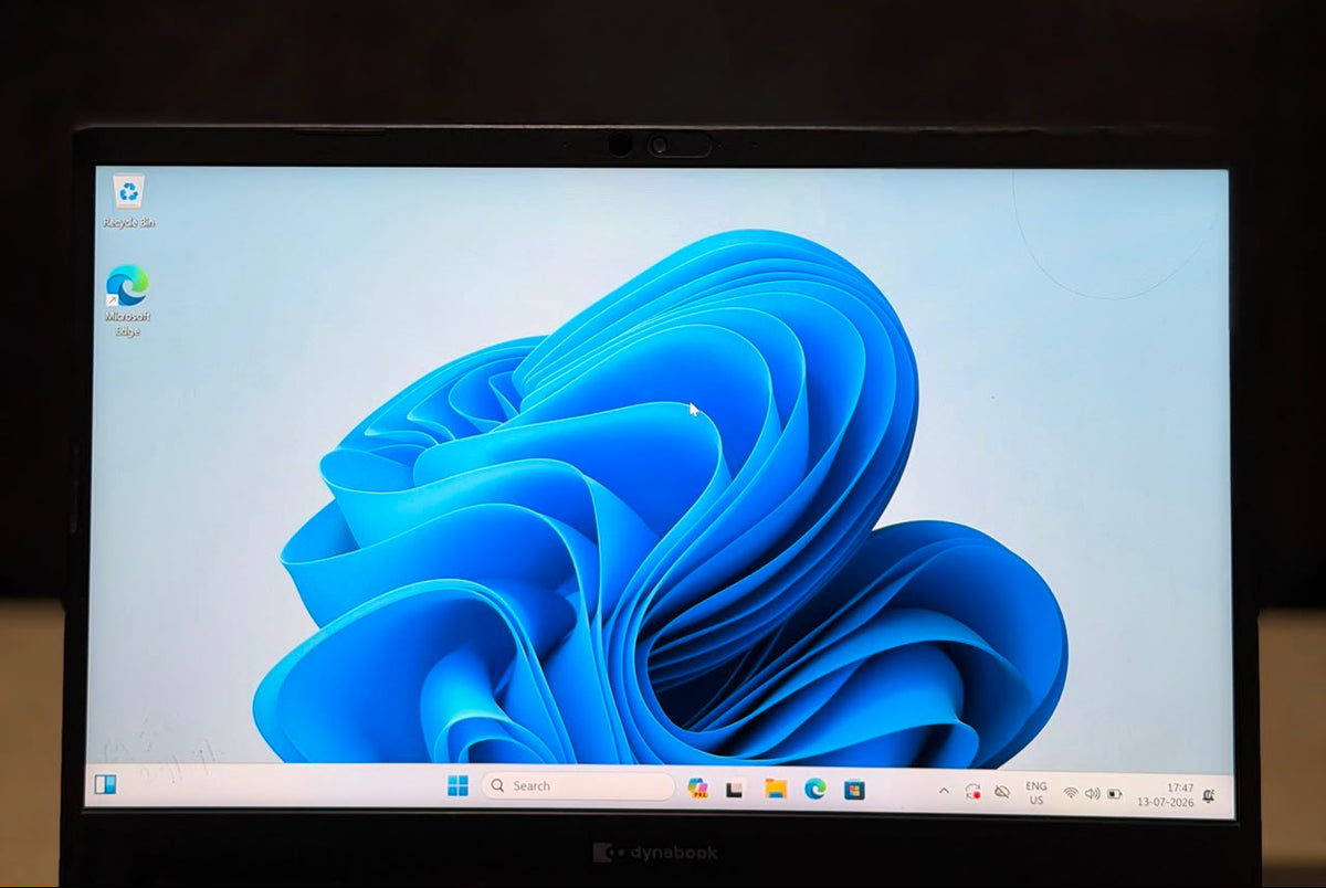 A black laptop computer displaying the Windows 11 desktop with its blue abstract wallpaper, set against a dark background.
