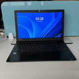 A Toshiba laptop with a black chassis and a blue screen wallpaper, displayed open on a white surface with a light blue background.