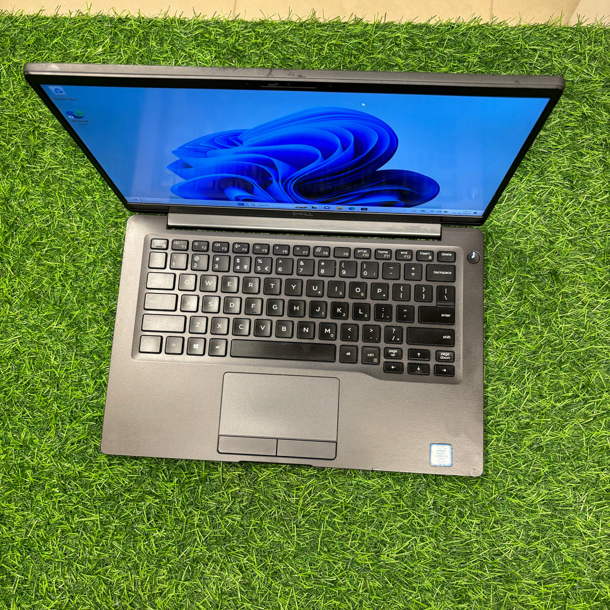 A silver Dell Latitude 7400 laptop on green background
